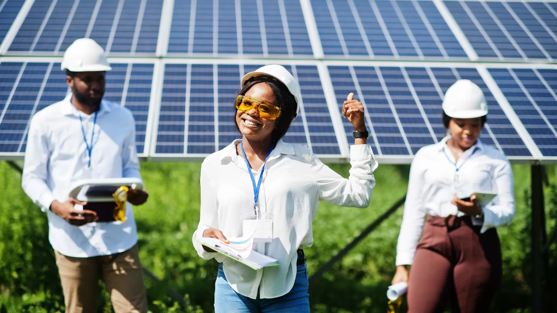 team of engineers standing in front or solar panels wearing hardhats